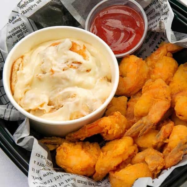 Bubba's Bistro fried shrimp with a side of creamy grits and ketchup, served on newspaper.