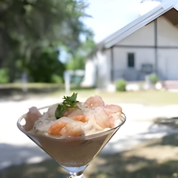 Bubba's Bistro shrimp cocktail in a martini glass with a blurred southern house background.