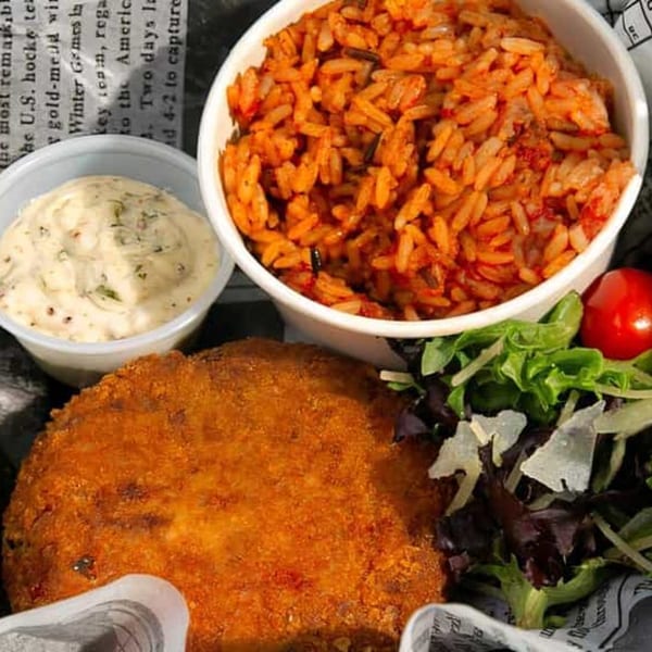 Bubba's Bistro's fried chicken, red rice, creamy sauce, and salad with newspaper lining.
