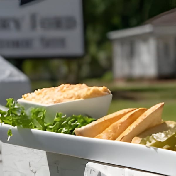 Southern pimento cheese dip with pita bread and lettuce on a white platter outdoors.