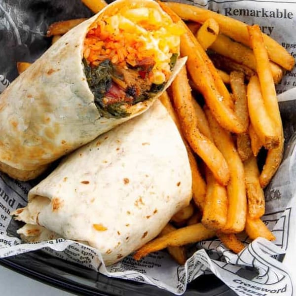 Two Bubba's Bistro burritos filled with rice and greens, served with seasoned fries on newspaper.