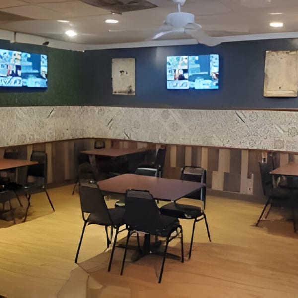 Interior of Bubba's Bistro with empty tables, chairs, and two TVs on the wall.