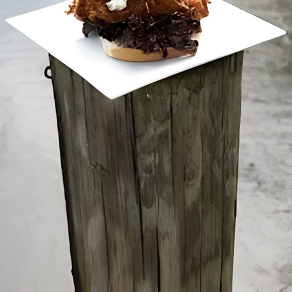 Bubba's Bistro's pulled pork sandwich with coleslaw on a white plate, atop a wooden post.