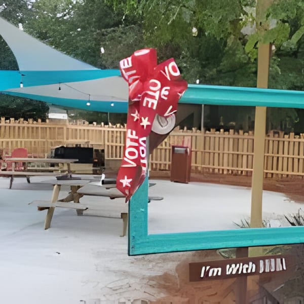 Outdoor patio at Bubba's Bistro with picnic tables, string lights, and a red "VOTE" ribbon.
